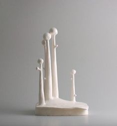 a white sculpture sitting on top of a table next to a gray wall and floor