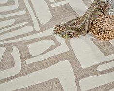 an area rug on the floor with a basket next to it and a blanket draped over it