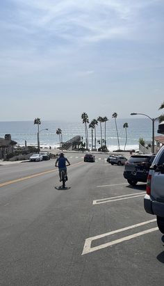 a man riding a skateboard down the middle of a street next to parked cars