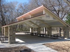 an outdoor shelter with picnic tables and trash can