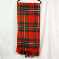 a red and green plaid scarf hanging on a white wall