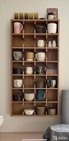 a wooden shelf filled with lots of cups and saucers on top of a table