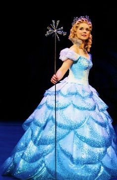 a woman in a blue dress holding a wand