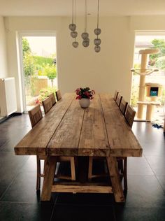 a wooden table with chairs around it and a vase on the table in front of it