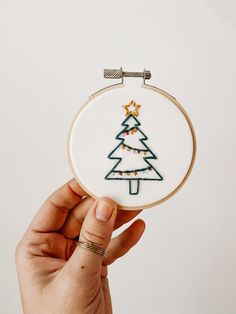 a hand is holding up a small embroidered christmas tree