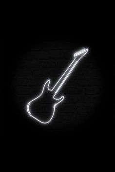 a neon guitar on a brick wall in the dark with its neck and pick - up