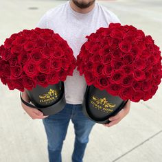 a man holding two black hats with red roses in it's center and the other one is wearing a white t - shirt