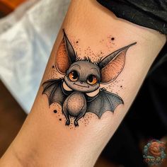 a small bat tattoo on the leg with orange eyes and an eyeball in the center