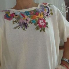 a woman wearing a white top with flowers on it