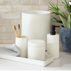 bathroom accessories including toothbrushes, soap dispenser and towel in front of brick wall