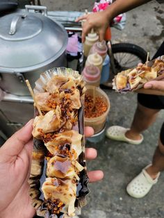 a person holding up some food in their hand while others stand around with other people