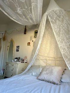 a white bed with a canopy over it's headboard and pillows on top of it