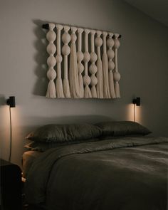 a bed with two lamps on either side of it and a wall hanging over the headboard