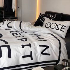 a bed with black and white pillows on top of it next to a night stand