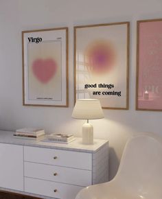 a white dresser topped with a lamp next to two framed pictures