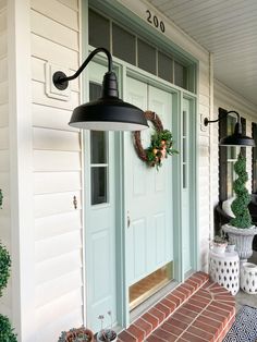 the front porch is decorated with wreaths and potted plants