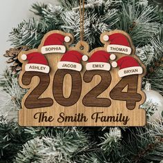 personalized christmas ornament with santa hats hanging on a tree in the snow