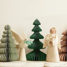 three paper christmas trees with angel figurines next to them