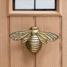 a golden bee door knocker on a wooden door