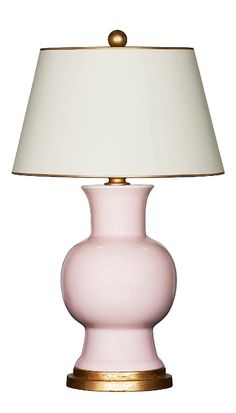 a pink table lamp with a white shade on the top and gold trim around the base