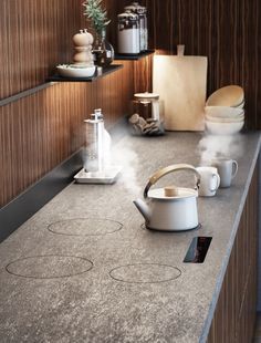 a kitchen counter with pots and kettles on it, steam rising from the stove