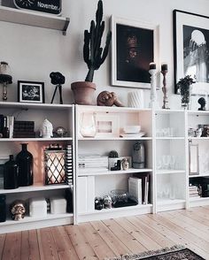 a living room filled with lots of white shelves and pictures on the wall above them