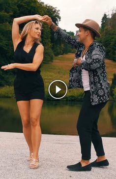 a man and woman dancing in front of a lake