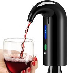 a person holding a wine glass next to a black faucet with red liquid pouring from it