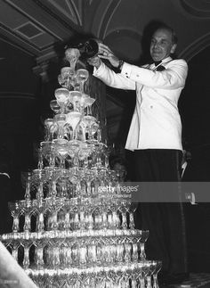 a man standing next to a large stack of wine glasses on top of a table