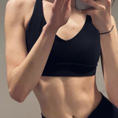 a woman taking a selfie with her cell phone while wearing a sports bra top