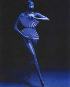 a woman is posing in a blue dress with an umbrella on her head and hands behind her back