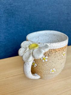 a ceramic coffee cup with a flower on the inside sits on a wooden table in front of a blue wall