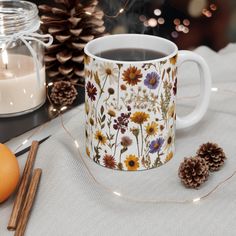 a cup of coffee on a table with pine cones and candles