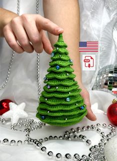 a woman is decorating a small green christmas tree with beads and ornaments around her