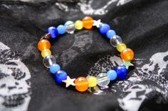 Aroace pride flag star beaded gemstone bracelet. The beads are the aroace flag colors (orange, yellow, white, blues) and holographic stars. ♥ Bracelet Size: - To find the size that fits you best, you can measure the circumference around your wrist; for a comfort/loose fit, add 2cm to that measurement ♥ Handcrafted With: ✔ High-quality gemstone beads ✔ Durable stretchy cord Thank you for visiting! If you have any questions, feel free to contact me!  Instagram: @FrogsMakingToast Pride Beaded Necklace, Multicolor Star-shaped Bracelet With Colorful Beads, Handmade Multicolor Star Bracelets, Colorful Star-shaped Jewelry For Gifts, Handmade Star-shaped Multicolor Jewelry, Handmade Multicolor Star-shaped Jewelry, Star-shaped Colorful Beaded Bracelets As Gift, Rainbow Star-shaped Bracelet For Gift, Handmade Rainbow Star Jewelry