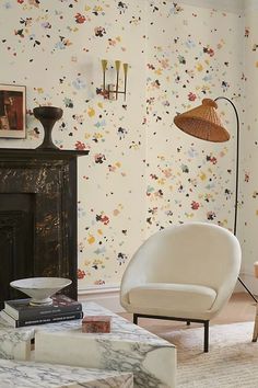 a living room with floral wallpaper and a chair in front of a fire place