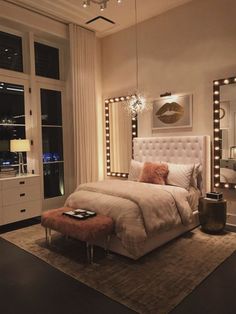 a bedroom with a bed, mirror and lights on the wall above it's headboard