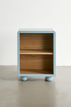 a small blue shelf sitting on top of a cement floor next to a white wall