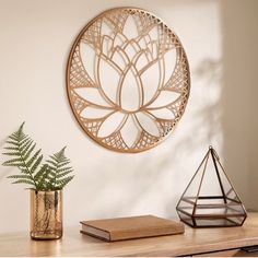 a wooden table topped with a plant and a metal circular wall hanging on the wall