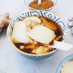 a bowl filled with food next to two spoons on top of a white table