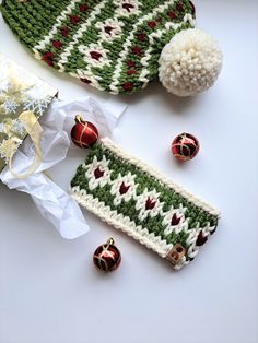 a knitted hat, mitten and ornaments on a white surface