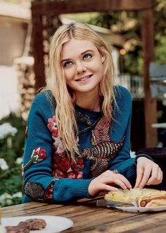 a woman sitting at a table with food in front of her and looking into the camera