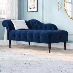 a blue couch sitting on top of a hard wood floor next to a white rug