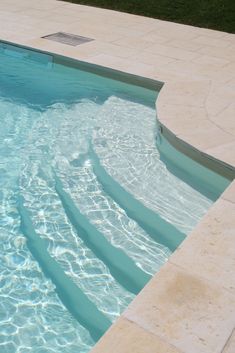 an empty swimming pool with clear blue water and steps leading up to the bottom level