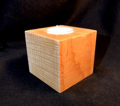 a small wooden block with a lit candle in it