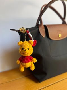 a crocheted winnie the pooh keychain hanging from a black bag