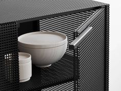 a white bowl sitting on top of a metal shelf next to a cup and saucer