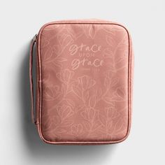 a pink case with white flowers and the words grace on it is sitting on a gray surface