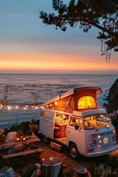 a vw camper van parked on the beach at sunset