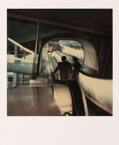 a man riding an escalator with his hand on the railing and another person standing next to him